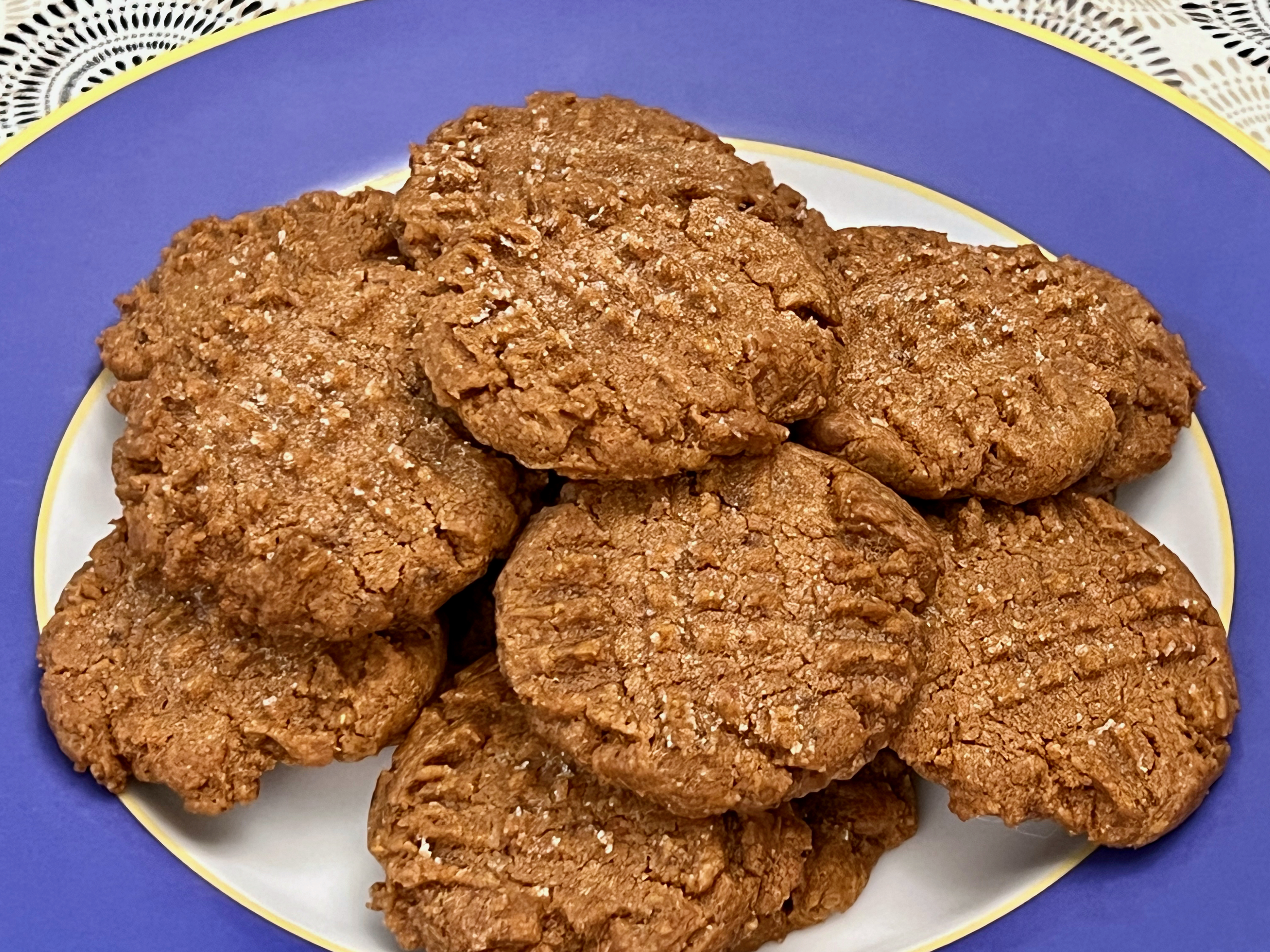Cross-hatched peanut butter cookies with a reddish hue, lightly covered in sugar crystals.