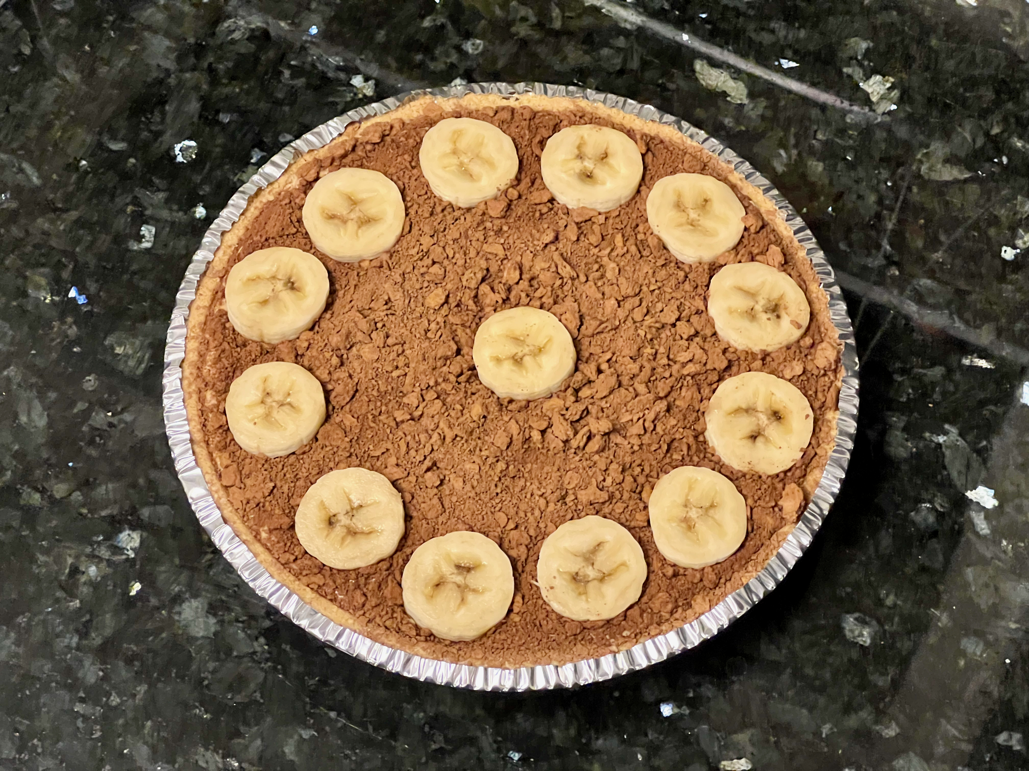 A pie with a graham cracker crust, covered in chocolate crumbs, with a ring of banana slices around the edge.