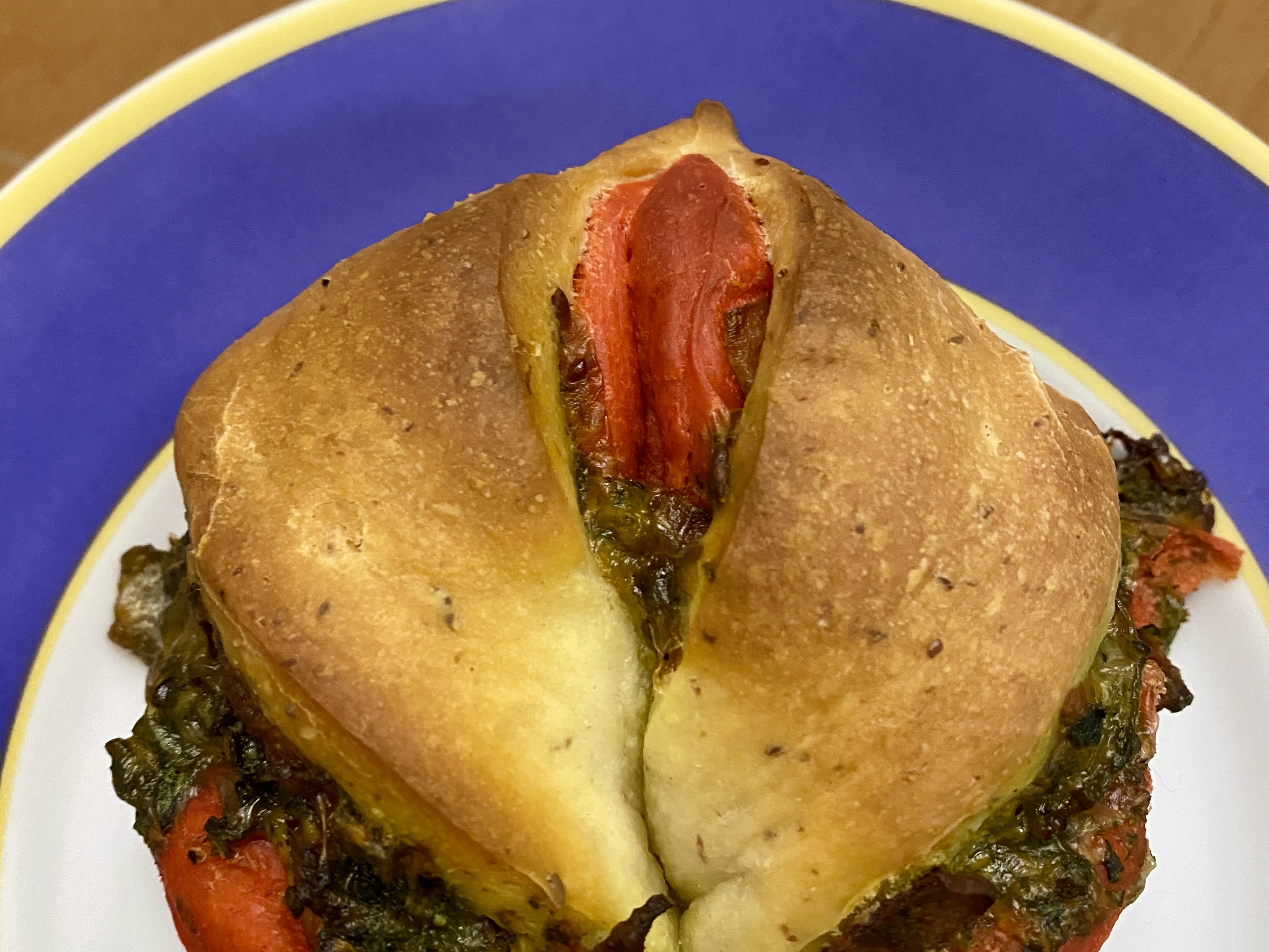 Twisted bread made with a layer of bright red dough and a layer of white dough with green pesto filling peeking through.