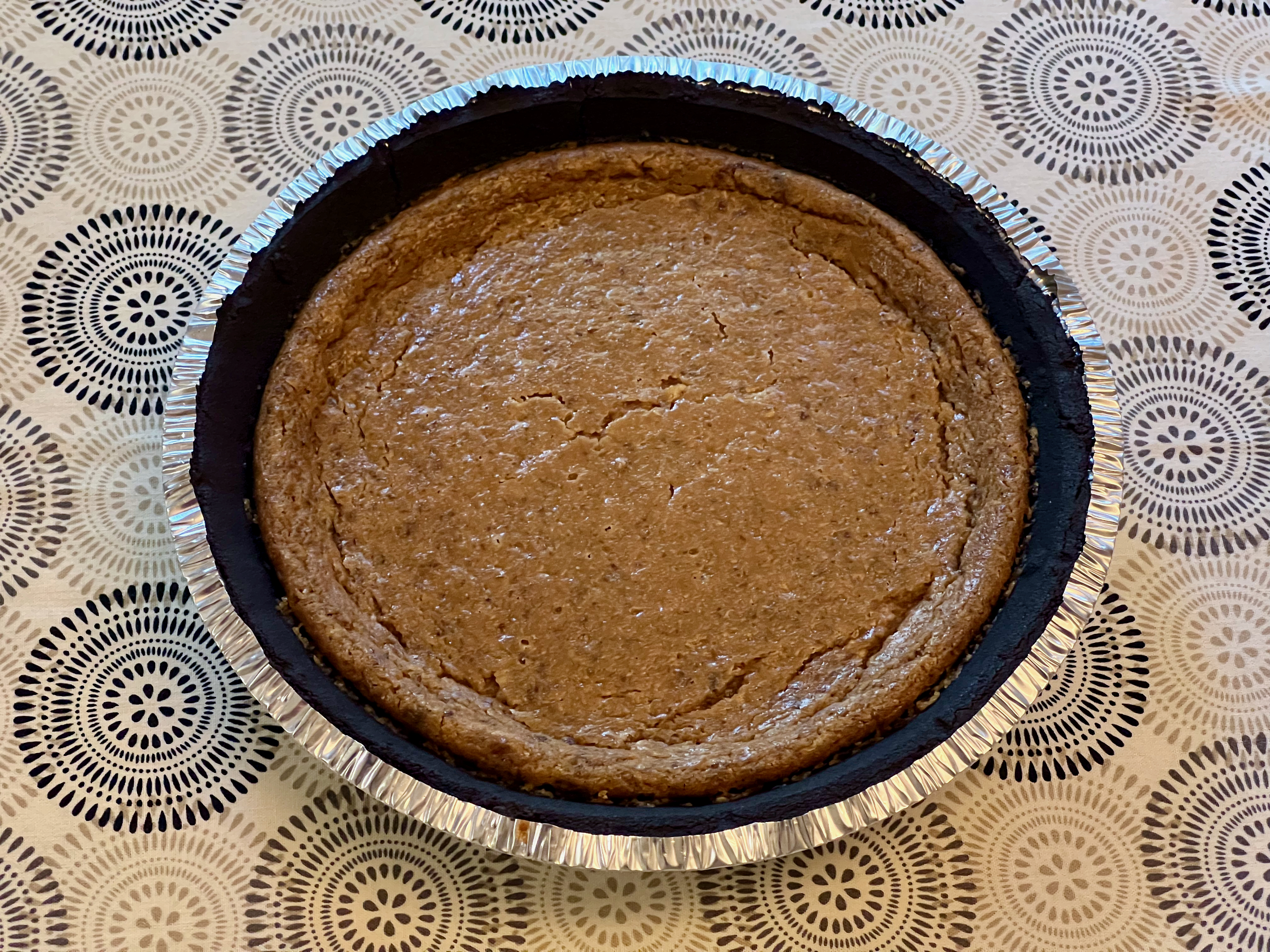 A glossy brown peanut custard pie with a chocolate cookie crust.